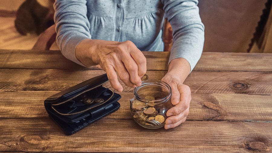 A man empties a jar of coins onto a table.