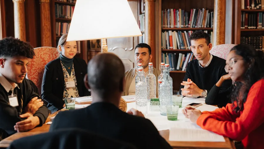 a group of people sit around the table in the middle of a discussion