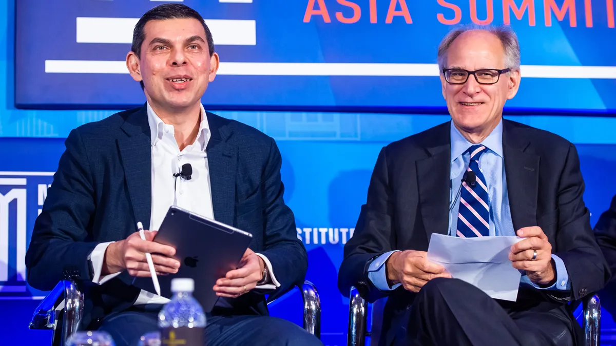 Two Men Sitting in Front of a Blue Background