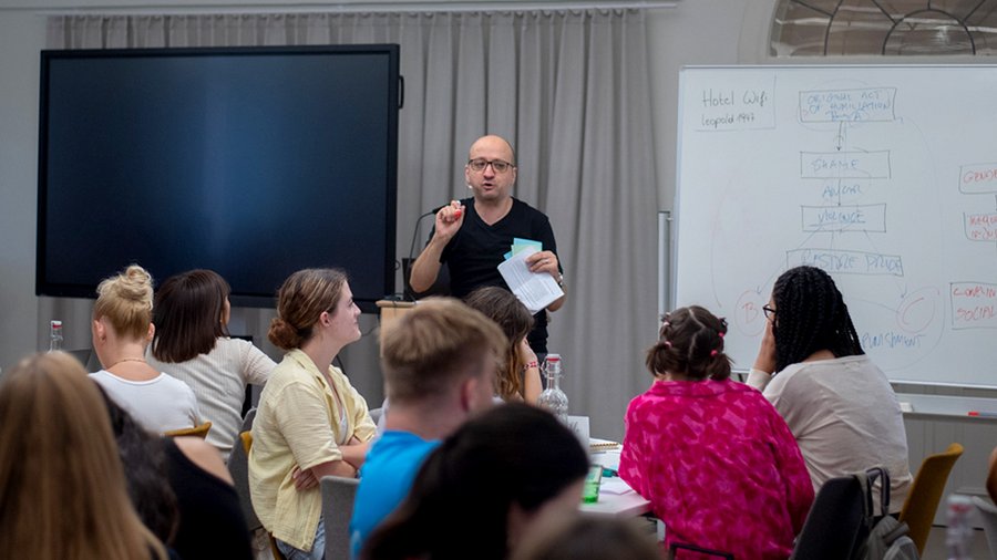 A man stands in front of a group of seated participants