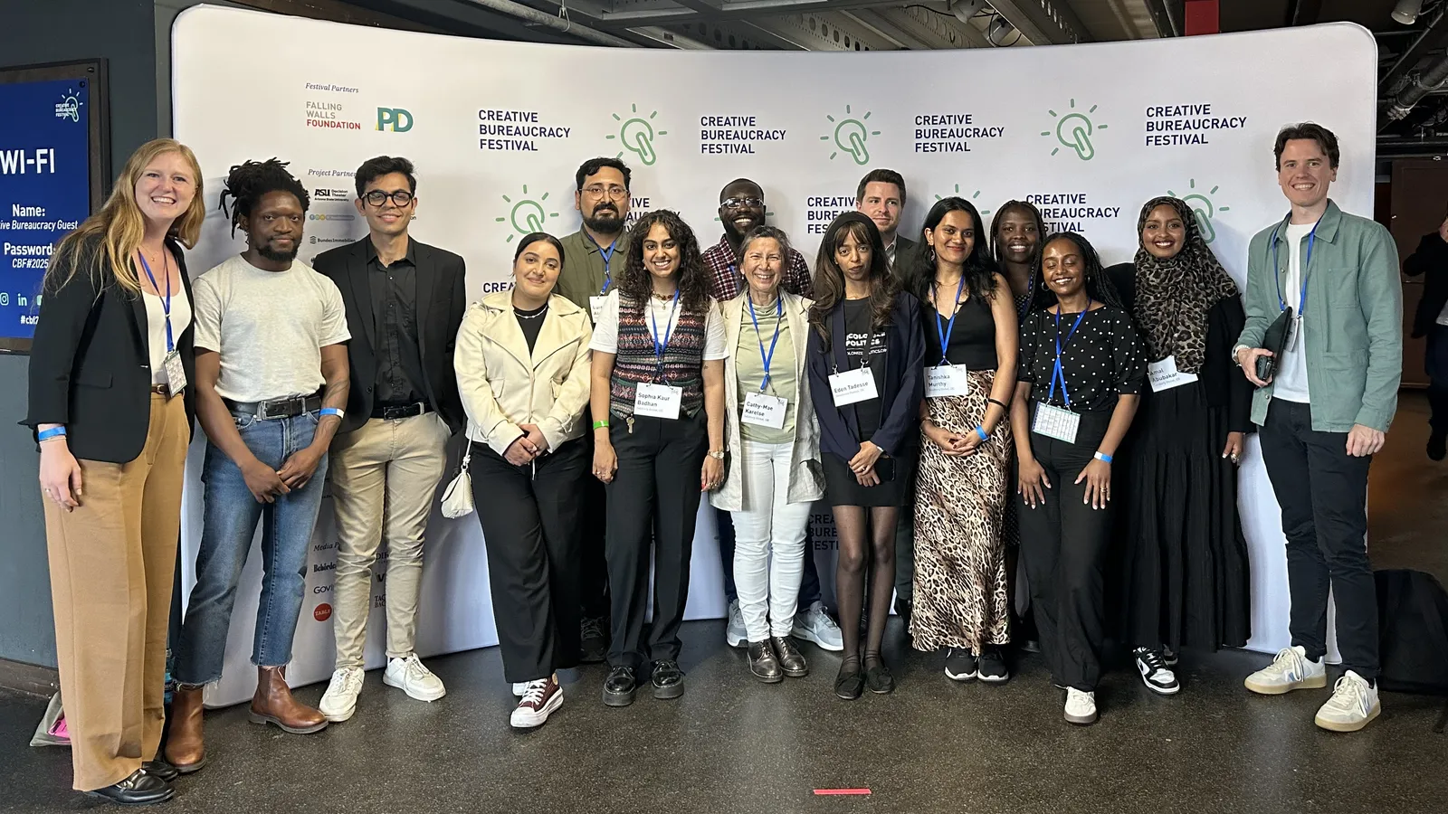 a large group of people smile in front of a branded background