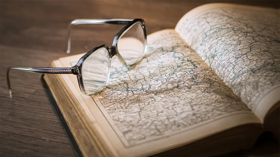 a pair of glasses laying on an open atlas book