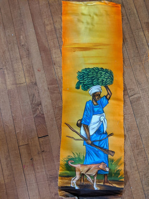 A painting of a person in blue and white clothing, walking with a dog by their side. They are holding some wood in one hand and carrying bananas on their head. The background is yellow and orange