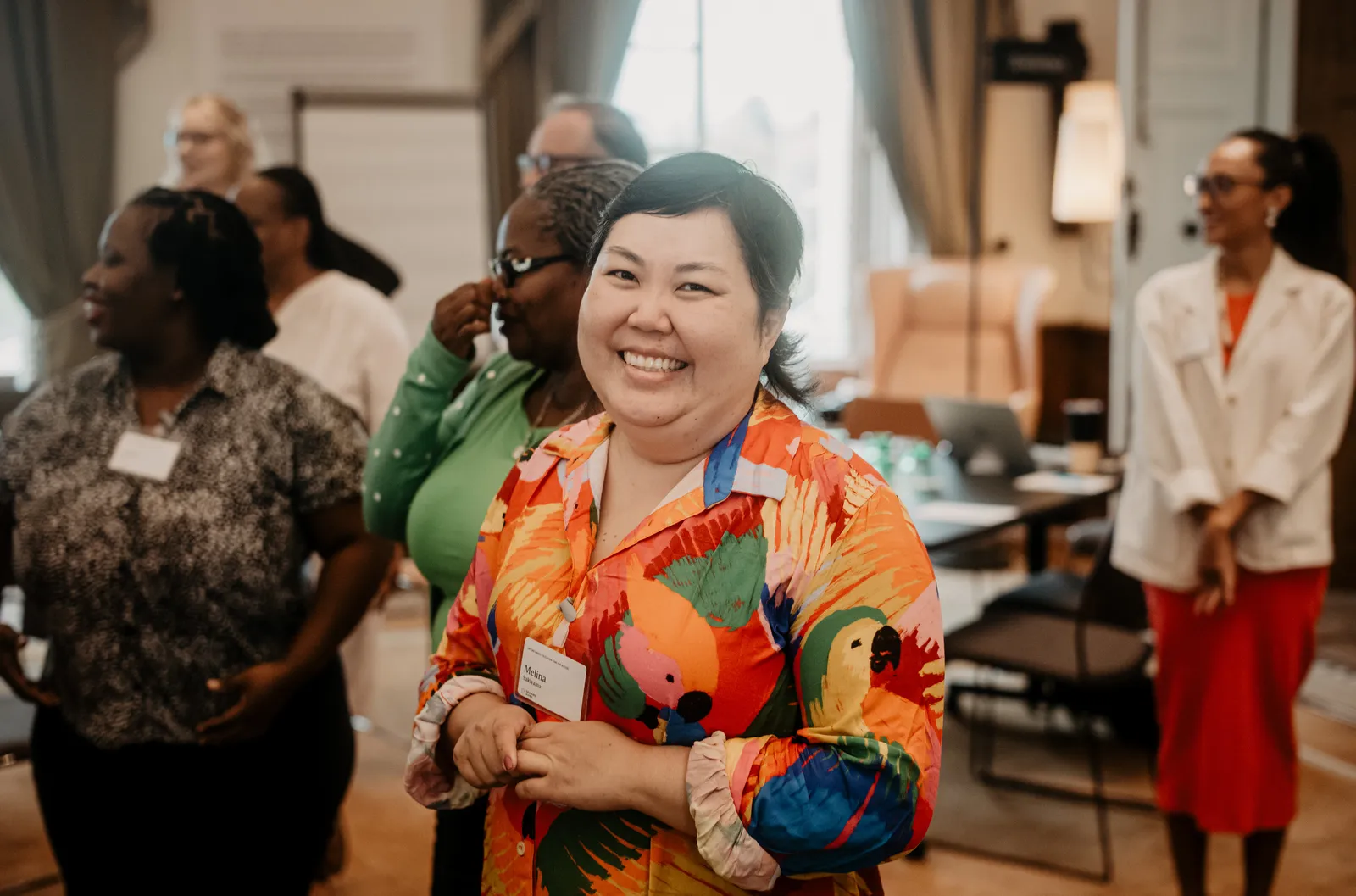 A woman wearing a colorful shirt smiles at the camera.