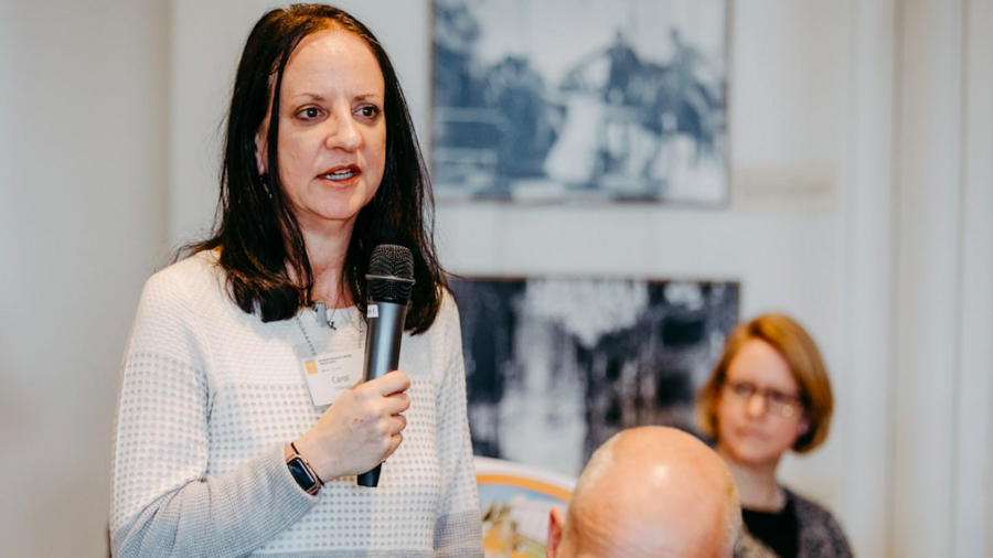 Carol O'Donnell holding a microphone and speaking