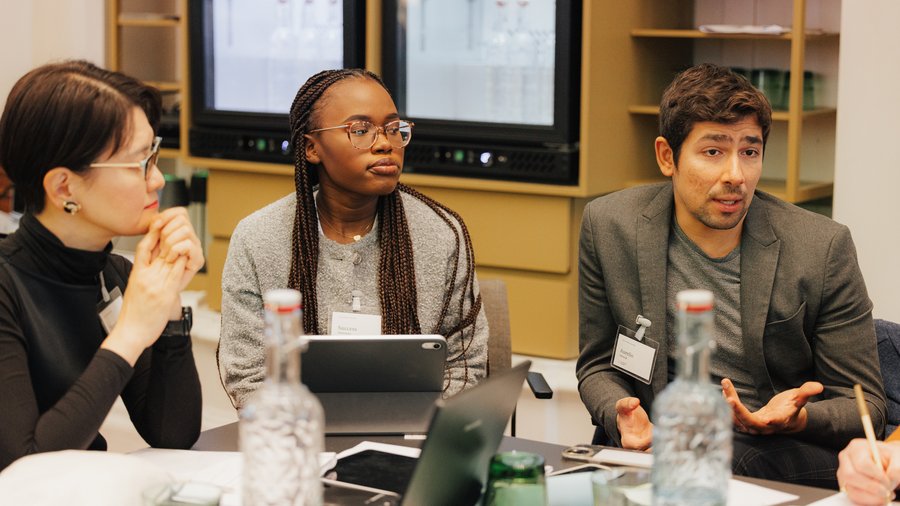 Success Areeveso in a discussion with other Salzburg Global Fellows and using a laptop on a table.