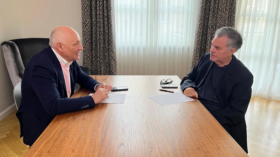 two men sitting across a table talking to each other