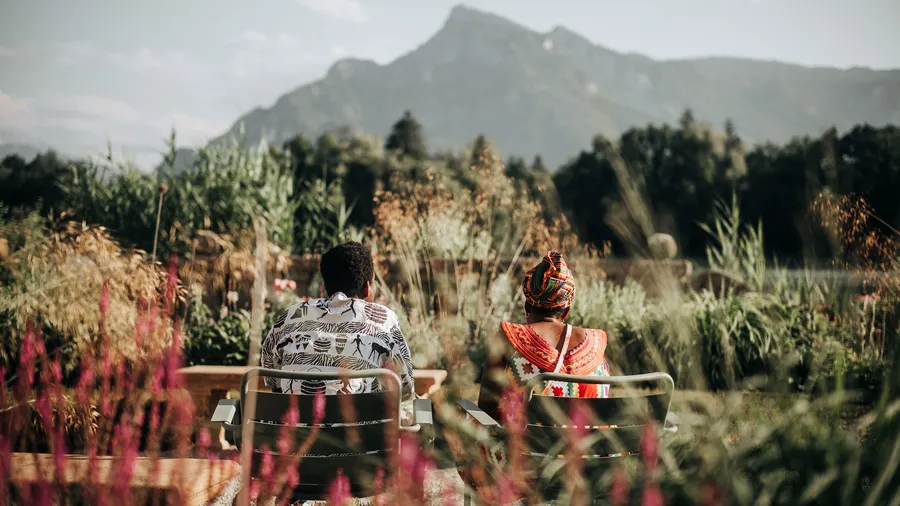Two individuals sit looking out towards the distance on the Mansbach Garden Parterre of Schloss Leopoldskron during the 2025 Salzburg Global Weekend. 