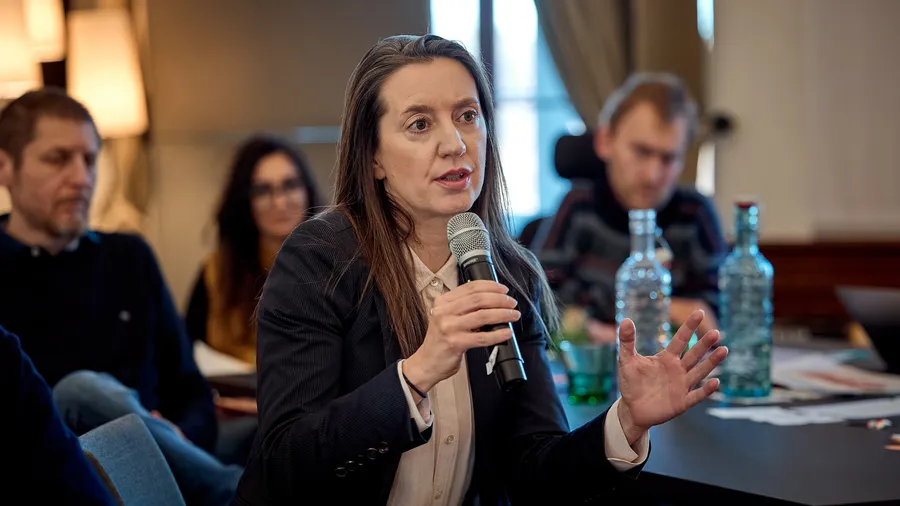 a woman speaks into a microphone while gesturing with her hand