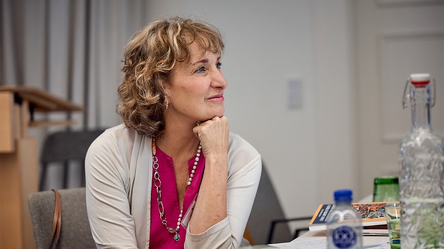 A woman sits with her head on her hand looking to her right