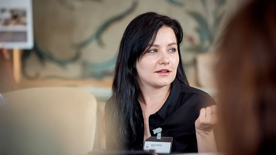 Daria, a woman with dark hair, looks to the right while speaking.
