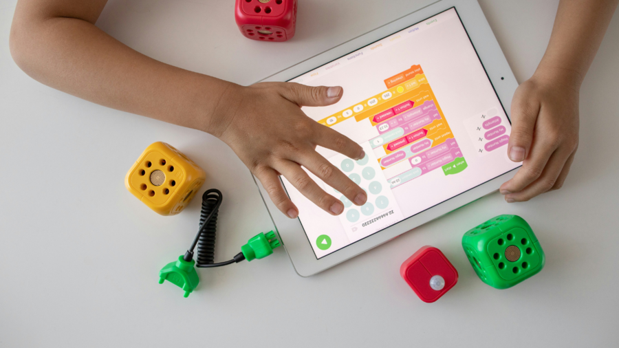 a photo taken from above of a child's hands using a digital tablet with some toys nearby