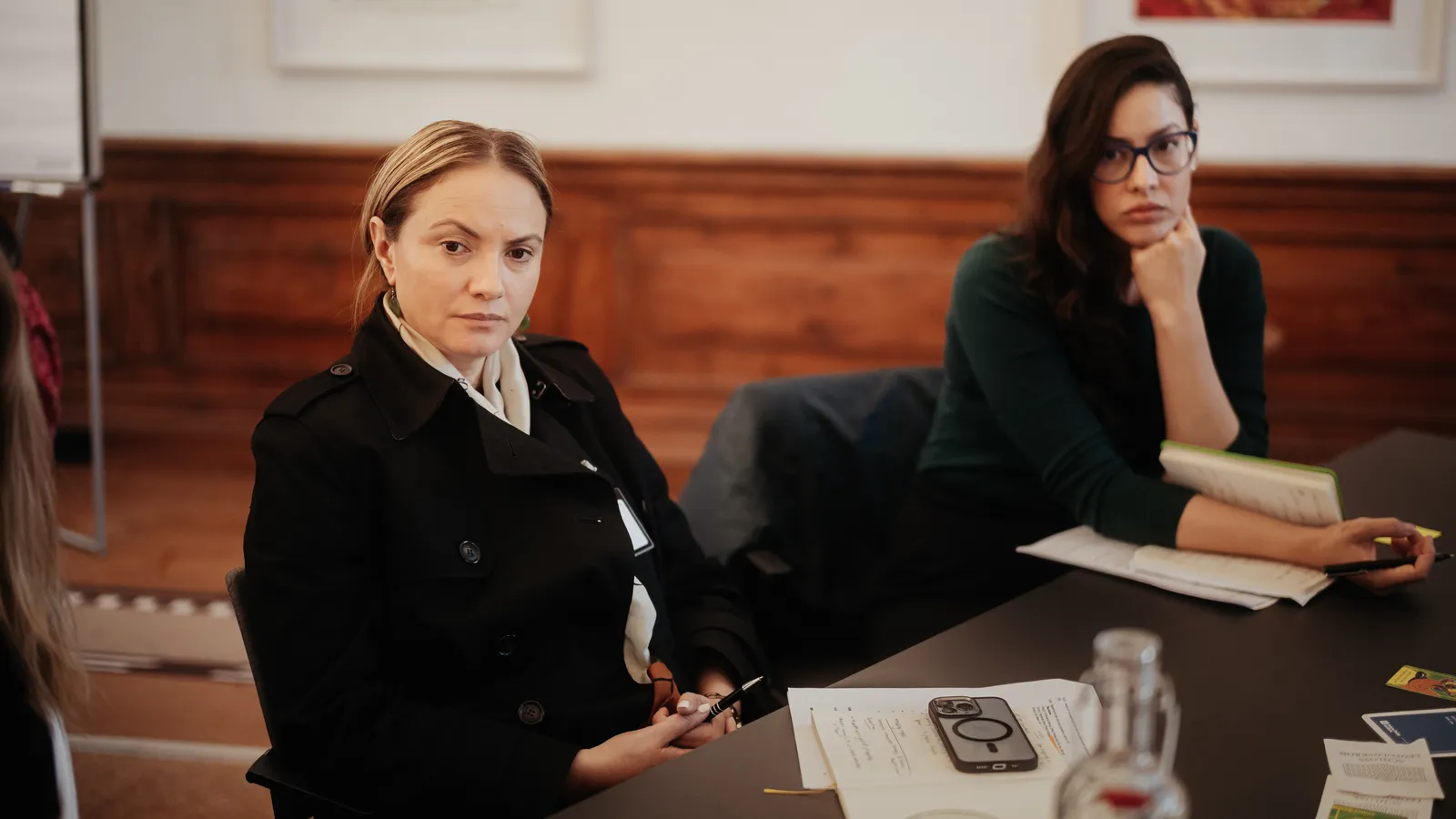 two women sit at a table listening intently