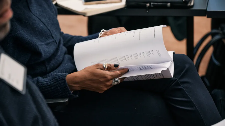 Hands of a Salzburg Global Fellow flip through pages of a directory booklet.
