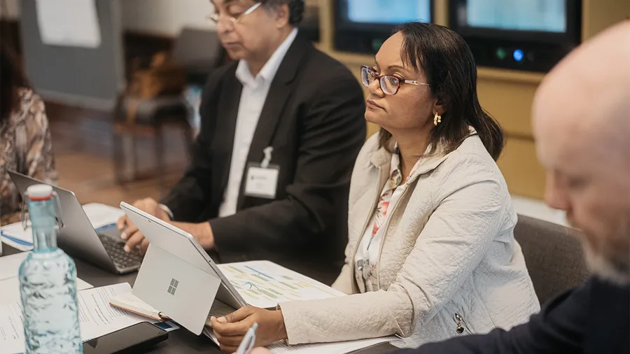a woman sits at a desk with a tablet and looks attentively to the left