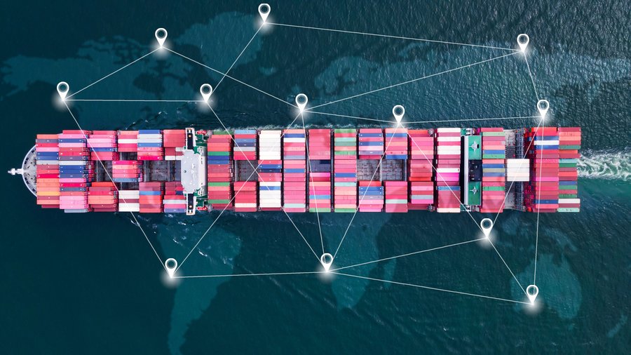 Aerial top view of a large container ship in the open ocean with a map in background.