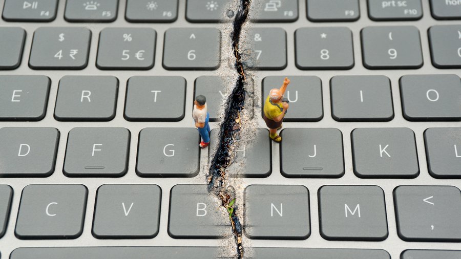 Split keyboard with two people facing away, representing internet confrontation, digital divide, social divide, and divided world conflicts.