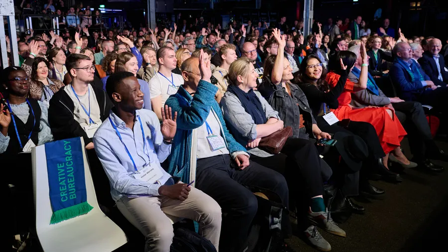 a group of people in a room smiles and some raise their hands
