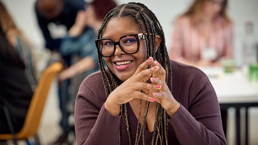 a woman with long braids and glasses smiles into the camera