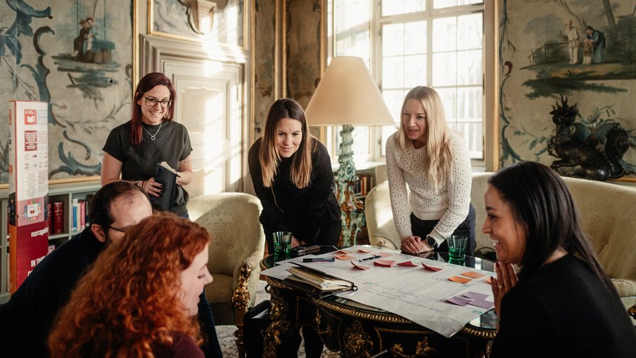 a group of people discuss while writing on a sheet of paper