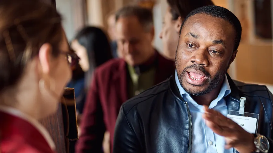 A photo of Mohamed Sidibay speaking to another Fellow at the International Law Fellows Network in Schloss Leopoldskron.
