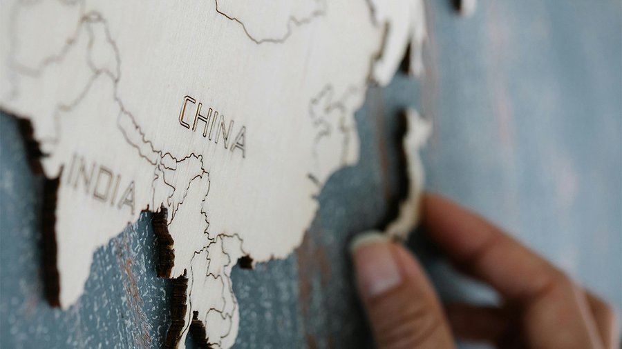 A hand touching a tactile map of Asia with India, China, and Japan visible.