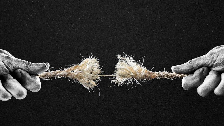 Two hands pull a fraying rope in opposite directions