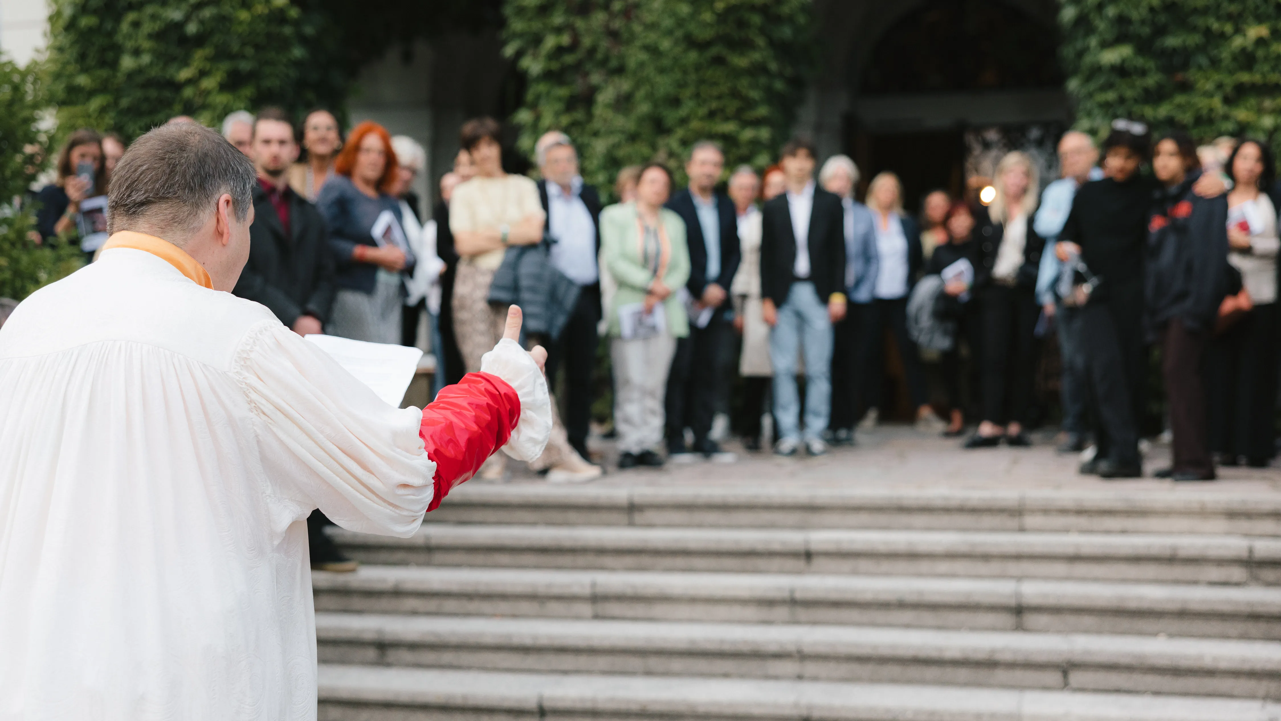 A man stands in a costume at the base of stairs where an audience watches him