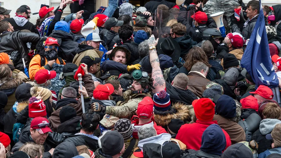 Washington, DC - January 6, 2021: A group of rioters clash with police trying to enter the U.S. Capitol building through the front doors