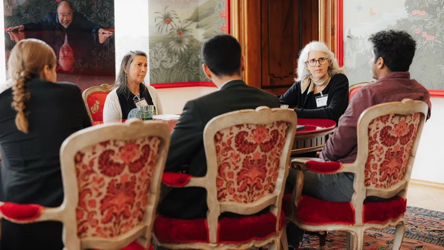 a group of individuals sit during a discussion in the Red Salon of Schloss Leopoldskron