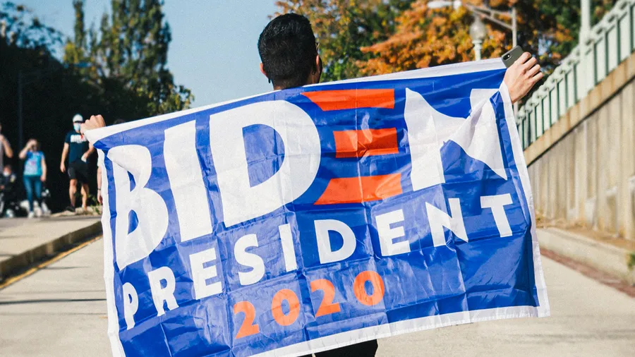 Man displaying "Biden President 2020" banner behind his back