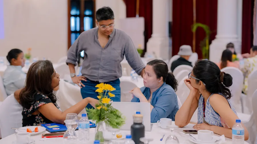 Four participants engage in a focused discussion around a table during a Salzburg Global peacebuilding workshop in Colombo, Sri Lanka.