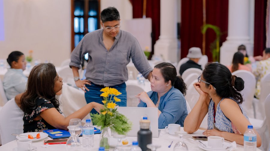 Four participants engage in a focused discussion around a table during a Salzburg Global peacebuilding workshop in Colombo, Sri Lanka.