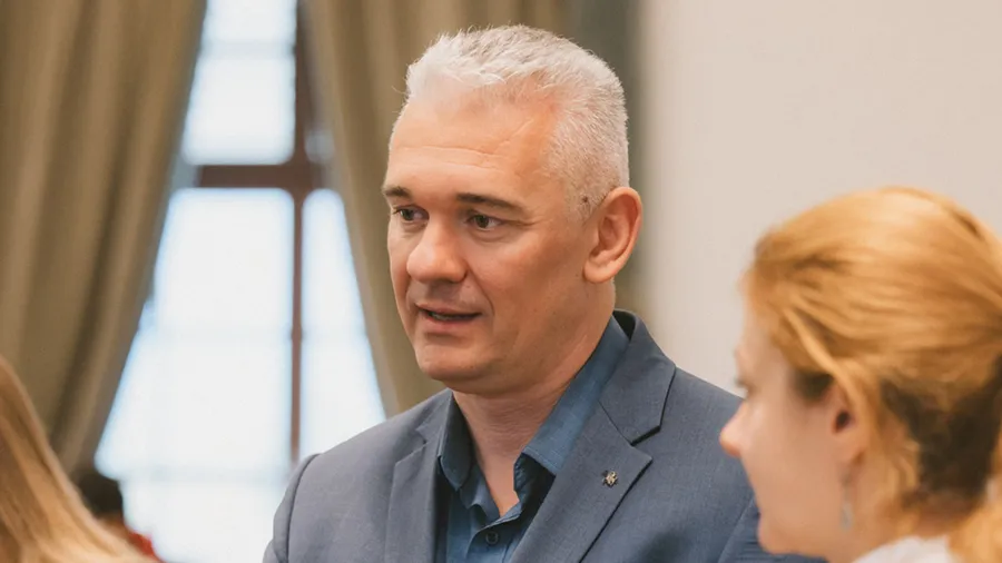 a man in a suit looks to the left while talking