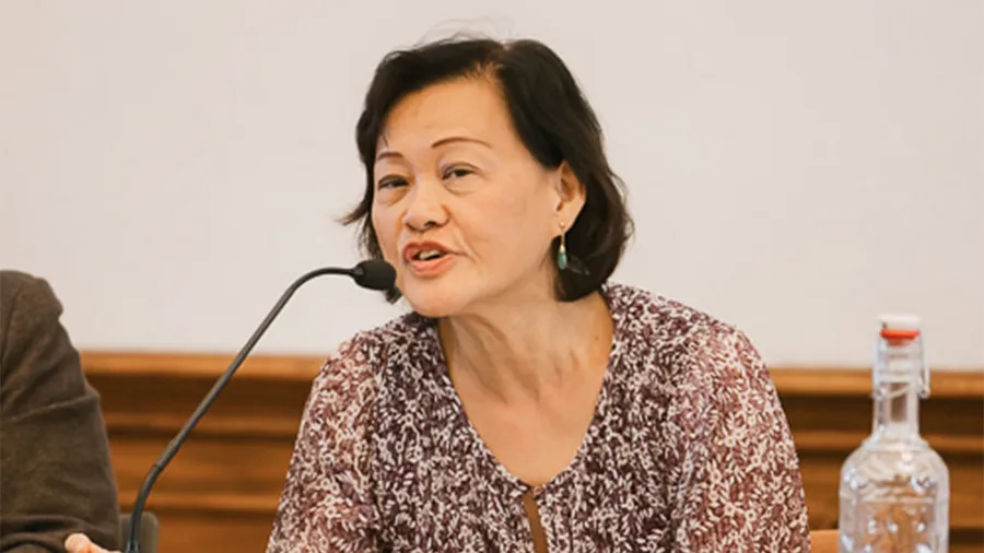 A woman with dark hair speaks into a microphone