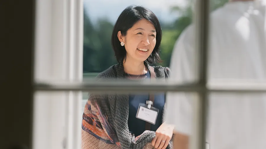 a woman stands through a glass door looking to the right smiling