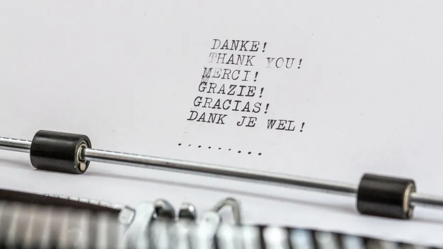 Paper in typewriter which includes the words Danke, Thank you, Merci, Grazie, Gracias, Dank je wel. 