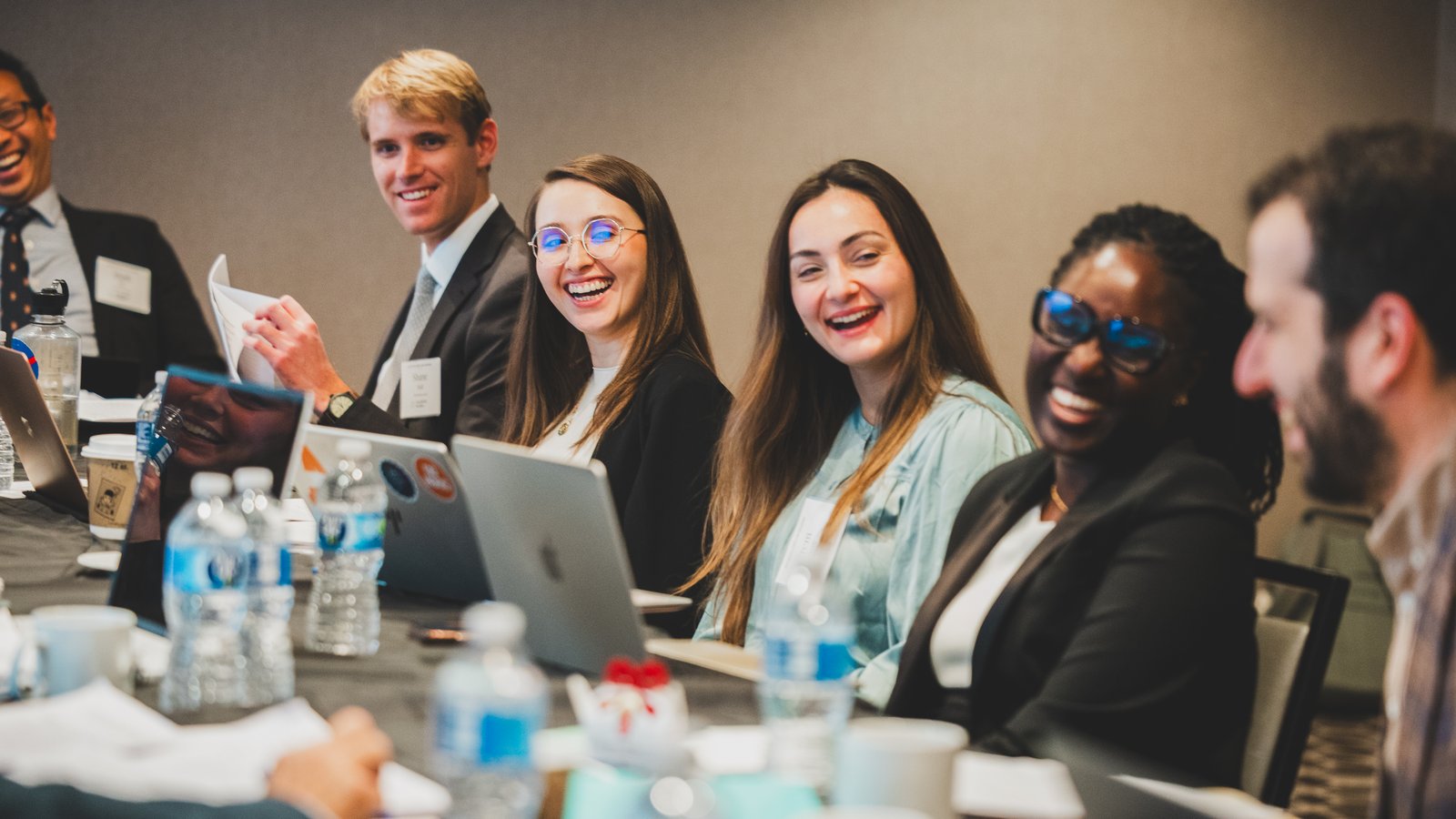 a few individuals sit next to each other at a table smiling and speaking together
