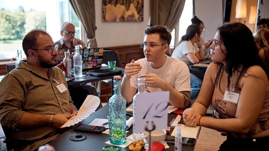 Three individuals sit at a table and engage in a lively conversation.