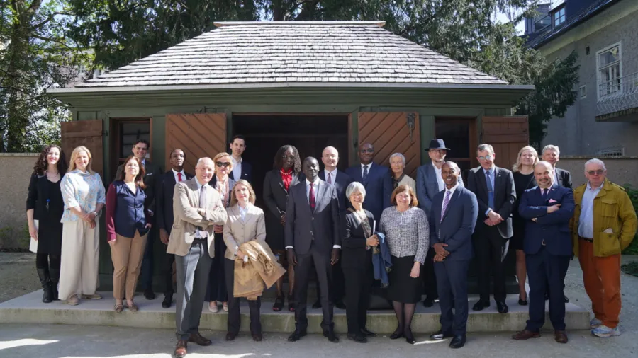 Group of people standing together in front of a small green cottage. 