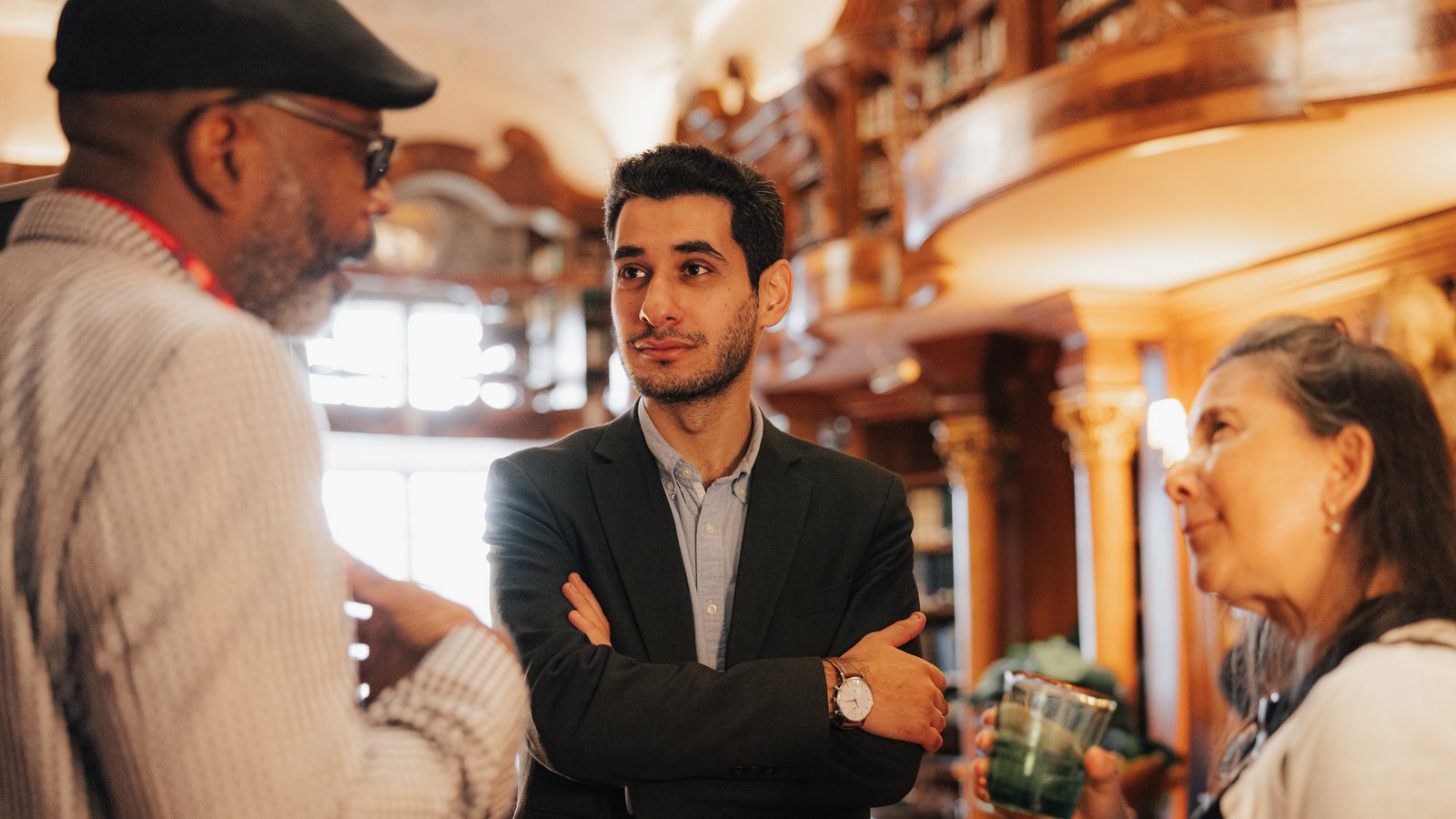 A group of three people stand in conversation in a library.