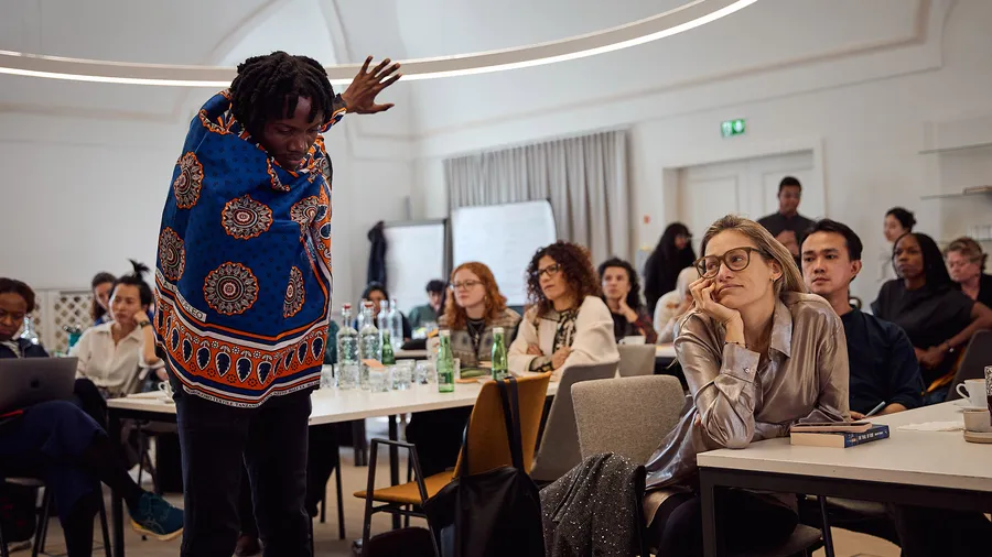 Samwel Japhet performs a dance in front of a group of Salzburg Global Fellows in Fellows Hall of Schloss Leopoldskron