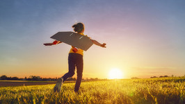 A photo of a child running through a field during sunset pretending to be a rocket.