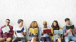 six people sitting and each reading a book while speaking to each other