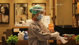Woman in protective gear putting on surgical gloves