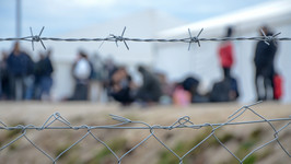 A barbed wire fence with blurry figures in the background