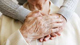 an elderly woman holds the hands of her caregiver on her chest